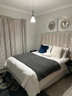 a bedroom with a large bed with white and blue pillows at The Blyde Pretoria in Pretoria
