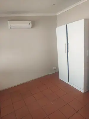 an empty room with a white wall and a red tile floor at Jakaranda house in Pretoria