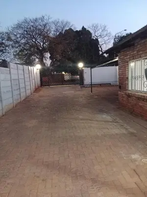 an empty parking lot with a fence and a building at Jakaranda house in Pretoria