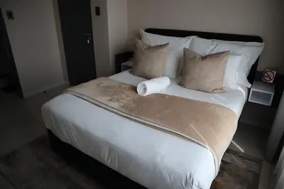 a large bed with white sheets and pillows at Luxury Modern Apartment Prime Midrand Location in Midrand