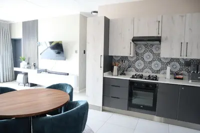 a kitchen with a wooden table and chairs and a stove at Luxury Modern Apartment Prime Midrand Location in Midrand