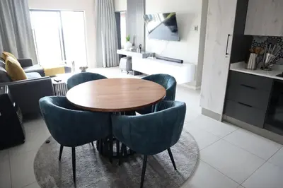 a living room with a wooden table and blue chairs at Luxury Modern Apartment Prime Midrand Location in Midrand