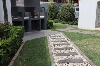 a garden with rocks and grass next to a building at Luxury Modern Apartment Prime Midrand Location in Midrand