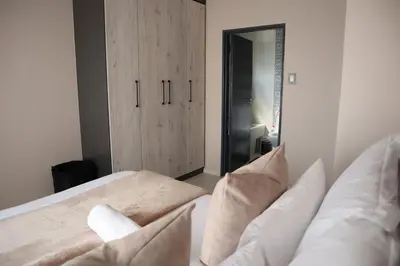 a bedroom with a bed with pillows and a cabinet at Luxury Modern Apartment Prime Midrand Location in Midrand