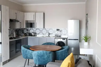 a kitchen with a wooden table and blue chairs at Luxury Modern Apartment Prime Midrand Location in Midrand