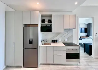 a kitchen with a sink and a refrigerator at The Trilogy Collection Luxury One Bedroom in Pretoria