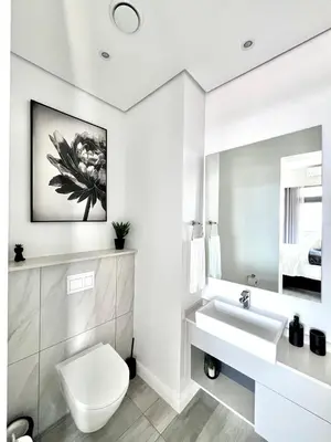 a white bathroom with a toilet and a sink at The Trilogy Collection Luxury One Bedroom in Pretoria