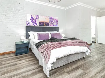 a bedroom with a large bed with purple pillows at Links & Lavender in Centurion