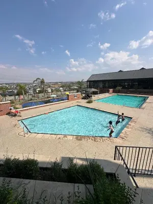 a large swimming pool with people playing in it at The luxury IN waterfall Midrand in Midrand