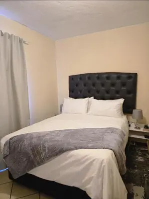 a bedroom with a large bed with a black headboard at THE Y's HOME in Centurion
