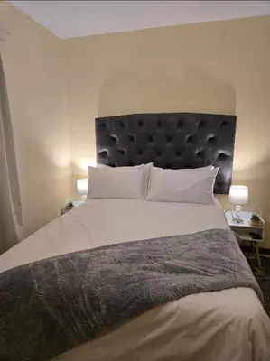 a bedroom with a large bed with a black headboard at THE Y's HOME in Centurion