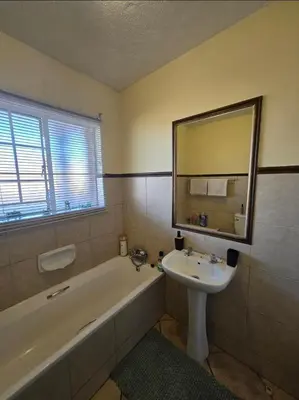 a bathroom with a sink and a tub and a mirror at THE Y's HOME in Centurion