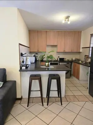a kitchen with a counter and two bar stools at THE Y's HOME in Centurion