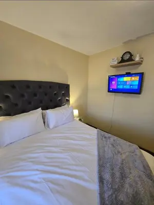 a bedroom with a bed and a tv on the wall at THE Y's HOME in Centurion