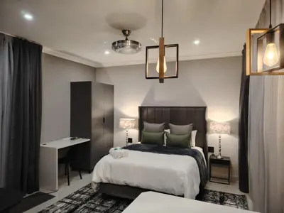 a bedroom with a bed and a table and a desk at F'leur Guesthouse in Mokopane