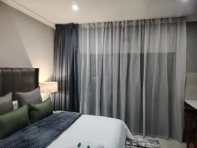 a bedroom with a bed and a window with curtains at F'leur Guesthouse in Mokopane