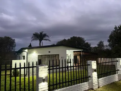 a white house with a fence and a palm tree at Soulfenda guest house in Graskop