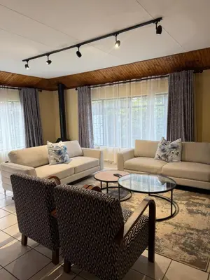 a living room with couches and tables and windows at Soulfenda guest house in Graskop