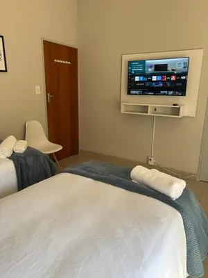 a hotel room with two beds and a flat screen tv at Catrachos Place in Pretoria