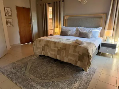a bedroom with a large bed with a blanket on it at Catrachos Place in Pretoria