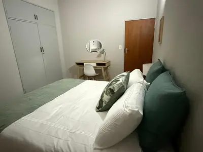 a bedroom with a bed with green and white pillows at Catrachos Place in Pretoria
