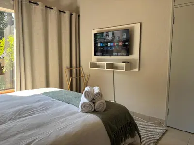 a bedroom with a bed with towels and a tv at Catrachos Place in Pretoria