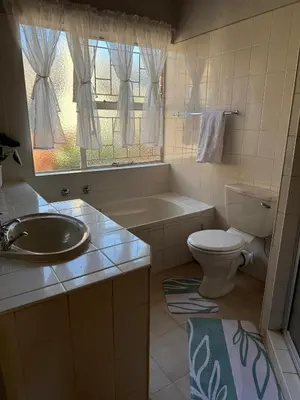 a bathroom with a sink and a toilet and a tub at Catrachos Place in Pretoria