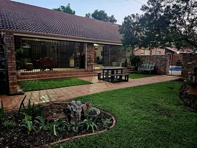 a garden with a bench and a statue in the yard at Chandané Guesthouse in Thabazimbi