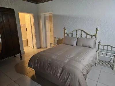 a bedroom with a large bed with a wooden headboard at Chandané Guesthouse in Thabazimbi