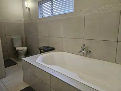 a white bath tub in a bathroom with a toilet at Chandané Guesthouse in Thabazimbi