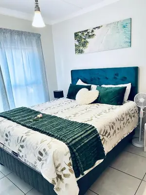 a bedroom with a large bed with a blue headboard at The Blyde bnb in Pretoria