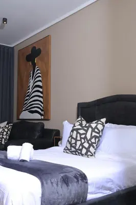 a bed with a black headboard and a black hat at Luxurious and Modern, Menlyn Maine Residences 825 in Pretoria