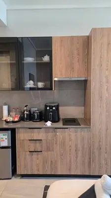 a kitchen with wooden cabinets and a black refrigerator at Luxurious and Modern, Menlyn Maine Residences 825 in Pretoria