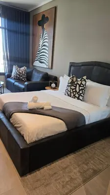 a large bed with a black headboard at Luxurious and Modern, Menlyn Maine Residences 825 in Pretoria