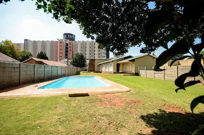 a swimming pool in a yard with a building at Airport Guest House in Kempton Park