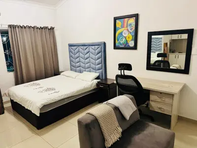 a bedroom with a bed and a desk and a chair at Airport Guest House in Kempton Park
