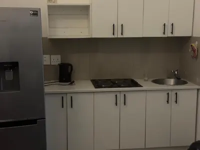 a kitchen with white cabinets and a sink at Airport Guest House in Kempton Park