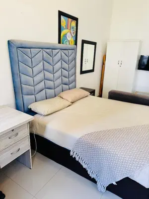 a bedroom with a large bed and a desk at Airport Guest House in Kempton Park