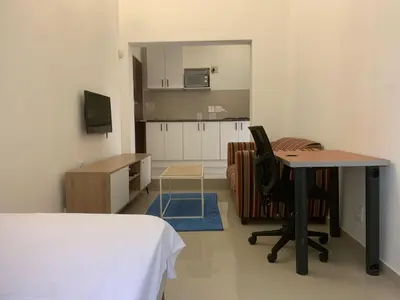a room with a desk and a table and a kitchen at Airport Guest House in Kempton Park