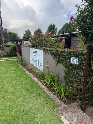 a sign for a house with flowers on a wall at De Trout Huis Guesthouse in Dullstroom