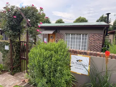a sign in front of a house with a fence at De Trout Huis Guesthouse in Dullstroom