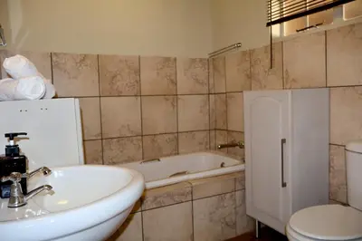 a bathroom with a sink and a tub and a toilet at De Trout Huis Guesthouse in Dullstroom