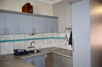 a kitchen with white cabinets and a sink at De Trout Huis Guesthouse in Dullstroom