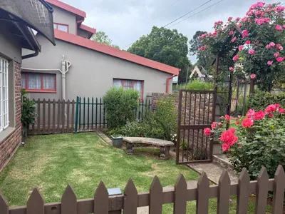 a backyard with a wooden fence and a bench at De Trout Huis Guesthouse in Dullstroom