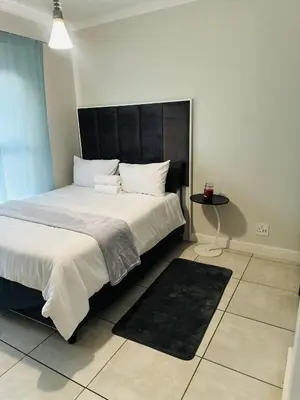a bedroom with a large bed and a table at The Blyde - Stay Iconic 2 bed Apartment in Pretoria