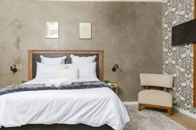 a bedroom with a large bed and a chair at Milan Coproperties in Kempton Park