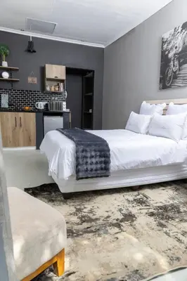 a bedroom with a large white bed and a kitchen at Milan Coproperties in Kempton Park