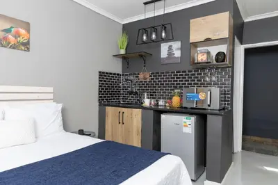 a bedroom with a bed and a small kitchen at Milan Coproperties in Kempton Park