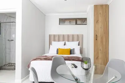 a bedroom with a bed and a glass table and chairs at Milan Coproperties in Kempton Park