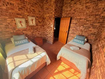 a room with two beds and a brick wall at Treeferns Trout Lodge in Dullstroom